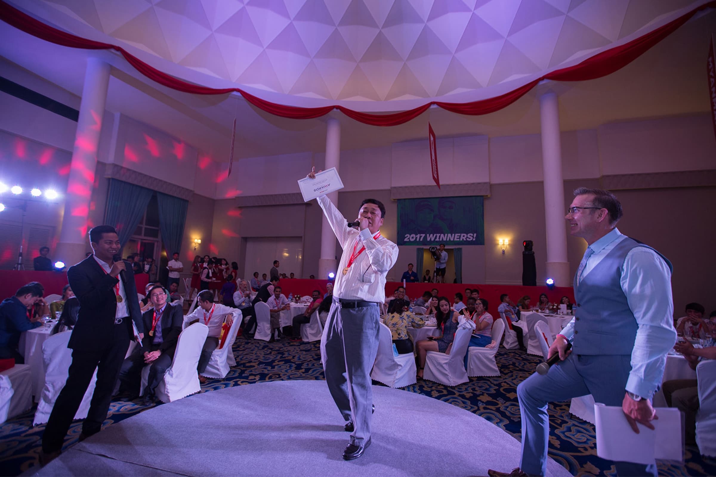 A winner takes the stage, certificate held high