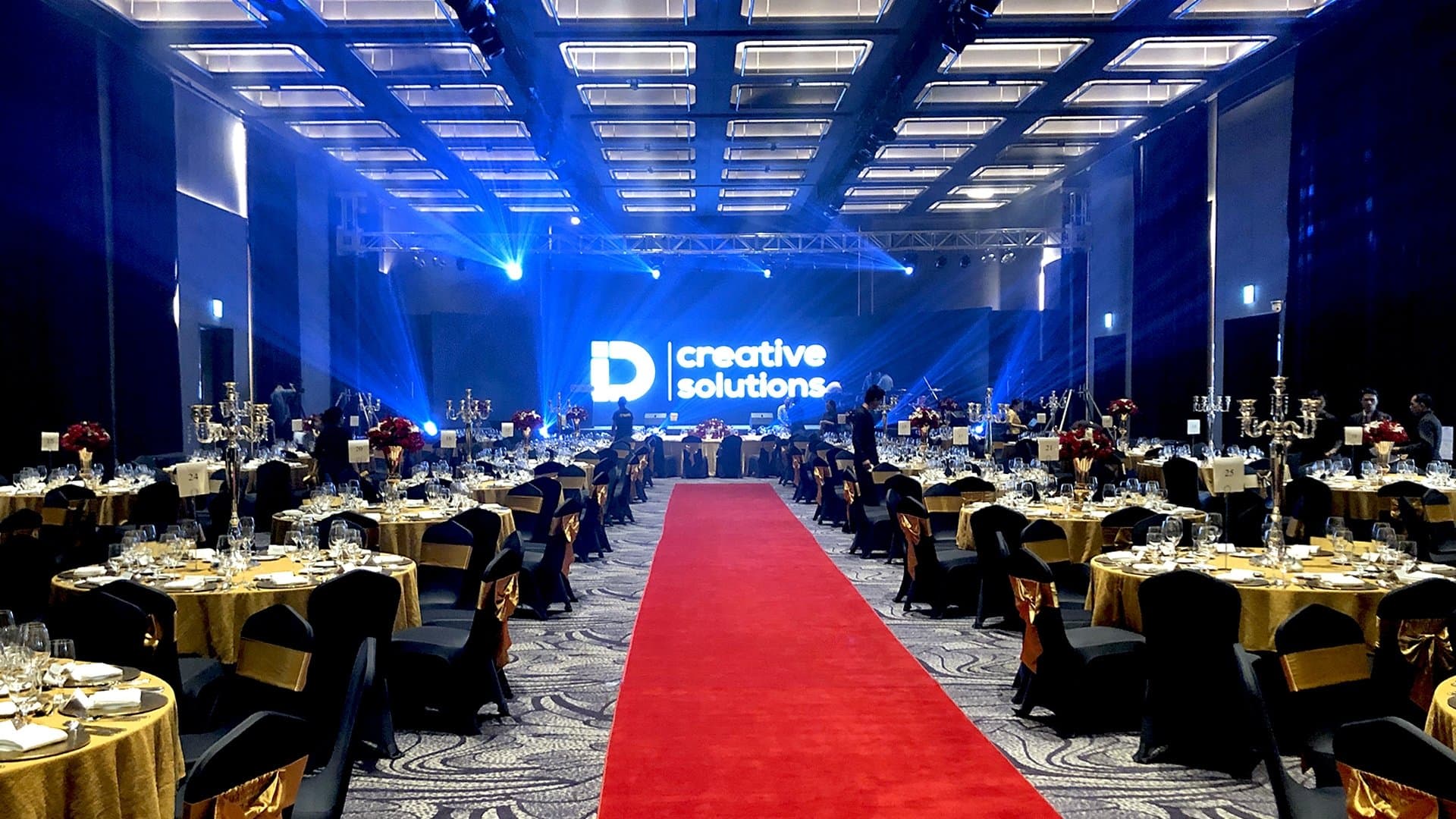 The ballroom during set-up — black and gold dressing, red carpet, iD test card on the LED