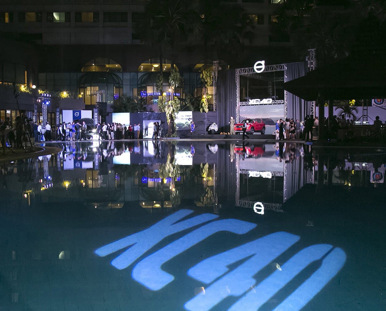 XC40 gobo across the pool at night, guests along the far side